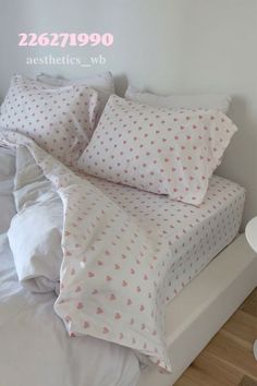 a bed with white sheets and pink hearts on it