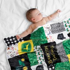 a baby laying on top of a white blanket next to a black and yellow pillow