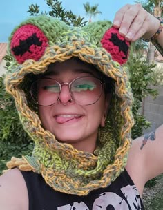 a woman wearing a knitted frog hat and glasses