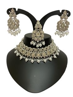 This Zari Silver Jewelry Set exudes elegance and sophistication, making it a perfect choice for weddings, festive events, or grand celebrations. The intricate craftsmanship showcases delicate silver details adorned with Kundan and pearl accents, creating a regal and timeless appeal. Whether paired with traditional or fusion outfits, this stunning necklace and matching earrings add a touch of luxury to your ensemble. Available now with quick international shipping! About this Silver Asian Jewelry Heavy Silver Bridal Necklace For Marriage, Silver Kundan Bridal Necklace For Marriage, Festive Silver Sets For Marriage, Silver Kundan Necklace For Marriage, Silver Sets With Intricate Design For Reception, Heavy Silver Bridal Necklace For Formal Occasions, Traditional Silver Bridal Accessories For Marriage, Silver Kundan Jewelry For Marriage, Silver Jewelry Sets For Marriage Festive Occasion