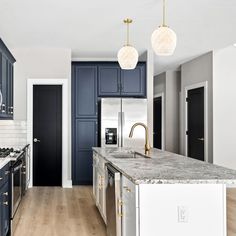 a large kitchen with blue cabinets and marble counter tops, along with stainless steel appliances