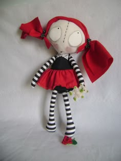 a doll with red hair and black and white striped dress is laying on a white sheet