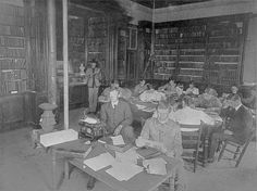 an old black and white photo of people in a library