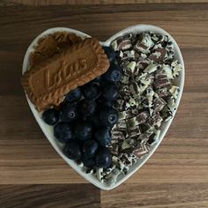 a heart shaped platter filled with chocolate, nuts and blueberries on top of a wooden table