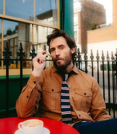 a man sitting at a table with a cup of coffee