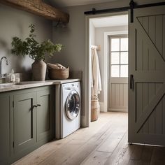 a washer and dryer in a room with wooden floors, green cabinets and open doors