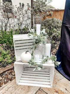 a white wooden crate with candles and greenery on the top is sitting outside in front of a house