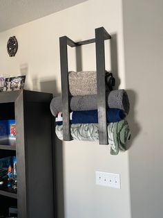 several folded towels are hanging on a rack in the corner of a room next to a bookshelf