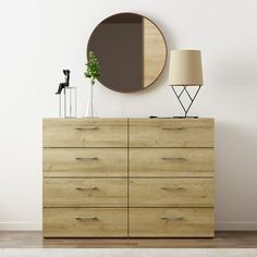 an empty room with a dresser and round mirror on the wall next to a lamp