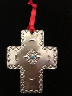 a metal cross ornament hanging from a red ribbon