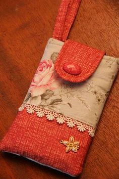 a cell phone case sitting on top of a wooden table next to a pink flower