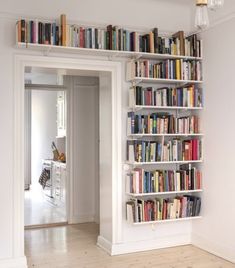 a bookshelf filled with lots of books in a living room next to a doorway