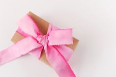 a pink ribbon tied on top of a piece of brown paper