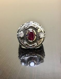 DeKara Designs ClearanceMetal- Sterling Silver, .925, 14K Yellow Gold.Stones- 1 Natural Oval Ruby 1.15 Carats, 2 Round Diamonds G-H Color SI2 Clarity, 0.25 Carats.  Size- 8.5.  FREE SIZING!!!! Art Deco Inspired elegantly handmade sterling silver and 14K yellow gold oval ruby and diamond engagement ring.  The center stone is set in a unique type of prong setting that is made in 14K yellow gold.  The ruby has one fiery round diamond in the same type of unique prong setting on each side.  The ring Luxury Handmade Ruby Ring, Ceremonial Oval Diamond Rings, Ceremonial White Gold Rings With Polished Finish, Handmade Diamond Rings For Formal Occasions, Luxury Silver Signet Ring With Center Stone, Oval White Gold Engraved Ring With Gemstone, Elegant Ceremonial Gemstone Signet Ring, Oval White Gold Engraved Ceremonial Ring, Formal Silver Ruby Ring With Engraving