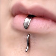 a woman's nose with an unusual metal ring on top of her lip and the bottom part of her tongue sticking out