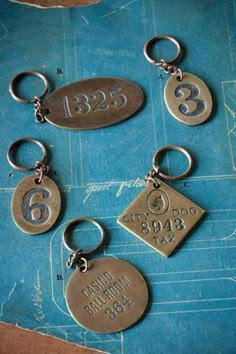 six different metal key chains with numbers and symbols on them, sitting on a blue piece of paper