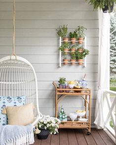 a white hanging chair sitting on top of a wooden floor next to a shelf filled with potted plants