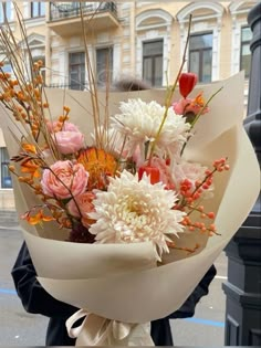 a woman holding a bouquet of flowers in front of a street light on a city street