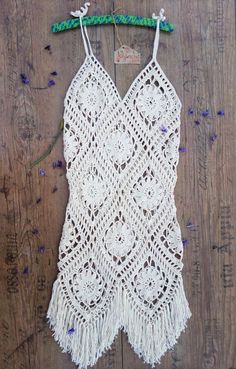 a white crocheted dress hanging on a wooden wall