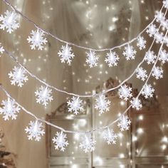 snowflakes are hanging from the ceiling in front of a mirror with lights on it