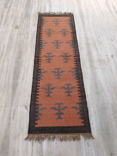 an orange and black rug on the floor with fringes around it's edges