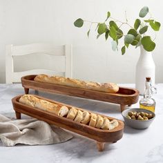 two wooden trays filled with bread and olives on a marble counter top next to a white vase