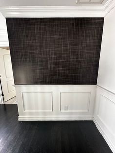 an empty room with white walls and black wood flooring, painted in dark tones