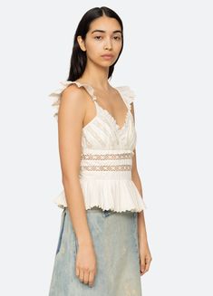 The Antonina tank top features flutter sleeves, lace inserts, ruffle detailing and pleated trim hem. Details: 100% polyester invisible back zipper designed for a slimmer fit style #PF24-007 model is 5'10'' and wearing a size 4 Summer Tank Top With Lace Trim And Ruffled Straps, White Fitted Tank Top With Ruffled Straps, Elegant Cotton Lace Tank Top, Fitted V-neck Tank Top With Ruffles, Feminine Fitted Tank Top With Lace Trim, Chic Spring Tank Top With Lace Patchwork, Chic Summer Tank Top With Lace Trim, Spring Lace Top With Scalloped Edges, Feminine Fitted Tops With Ruffled Straps