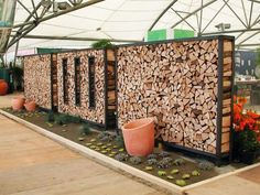 there are many logs on display in the garden center, with potted plants and flowers