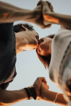 two people standing next to each other with their hands in the air and one person kissing