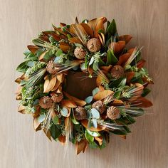 a wreath with leaves and pine cones on a wooden surface, top view from above