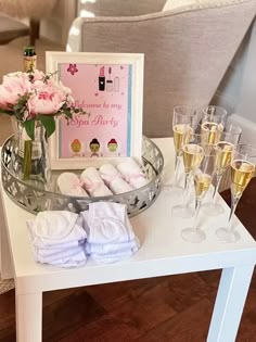 a table with champagne glasses and pink flowers on it next to a sign that says welcome to my big sister