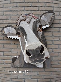 a cow made out of wood sitting on top of a brick wall