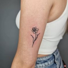 a small flower tattoo on the left arm