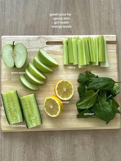 a cutting board topped with sliced up green apples and cucumbers next to slices of lemon