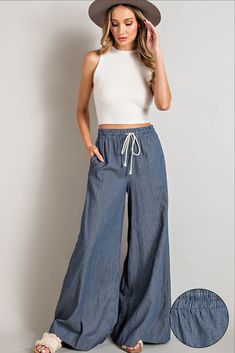 High waisted wide leg pants made with a smocked waist, waist tie, and side pockets in a washed denim. Summer Wide-leg Jeans With Elastic Waistband, Summer Denim Wide Leg Pants With Elastic Waistband, Medium Wash Wide Leg Bottoms With Elastic Waistband, Medium Wash Wide-leg Pants With Elastic Waistband, Medium Wash Wide-leg Bottoms With Elastic Waistband, Summer Cropped Wide Leg Pants In Medium Wash, Tie Pants, High Waisted Wide Leg Pants, Wideleg Pants