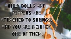 there is a quote about dolls hanging from strings on the table with flowers in the background