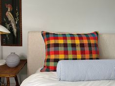 a bed with two pillows on it next to a lamp and painting in the background