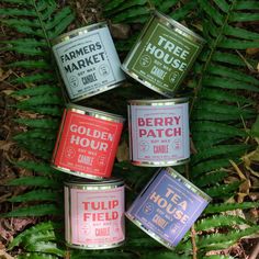 four tins of food sitting on the ground in front of some plants and leaves