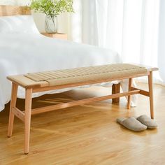 a wooden bench sitting on top of a hard wood floor next to a white bed