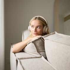 a woman wearing headphones sitting on a couch with her arms folded over the back