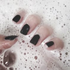 three black and white nail polishes in a bubbley bathtub with bubbles on the water