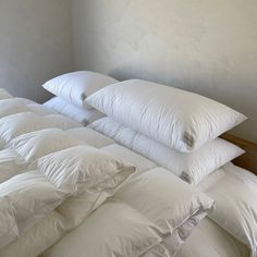 a pile of white pillows sitting on top of a bed