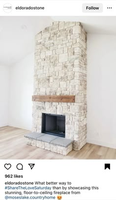 an empty room with a stone fireplace and hardwood floors in the corner, white walls