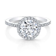 a white gold engagement ring with round diamonds on the band and an halo style center stone