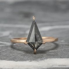 a gold ring with a black diamond on it's side, sitting on top of a table