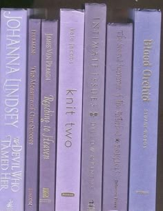 a row of purple books sitting on top of a shelf