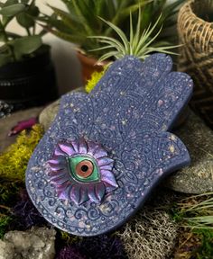 a blue bird shaped planter with an eye in it's center surrounded by succulents