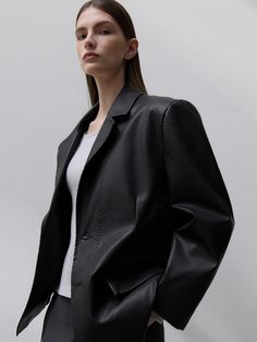 This product is a Section Faux Leather Jacket that offers a sleek and contemporary look with its clean design and sharp tailoring. The jacket provides a luxurious feel and appearance, while being a conscious choice with its faux leather material. It is structured to deliver a smart fit that complements both casual and formal outfits. - The jacket features a refined faux leather finish, presenting a polished and versatile outerwear option.- Its precise cut and tailored design ensure a flattering fit that enhances the silhouette.- The jacket includes subtle detailing that adds depth to the simple yet sophisticated style.- Built for both style and practicality, the interior is lined for additional comfort and warmth. Sleek Faux Leather Blazer With Notch Lapel, Modern Black Outerwear With Pressed Crease, Modern Single Breasted Leather Jacket With Notch Lapel, Sleek Leather Jacket For Business Casual In Fall, Sleek Single Breasted Leather Jacket For Work, Modern Leather Jacket For Office In Winter, Tailored Modern Leather Jacket For Fall, Tailored Sleek Leather Jacket For Fall, Modern Solid Outerwear For Office