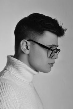 black and white photograph of a young man with glasses looking to his left, wearing a turtle neck sweater